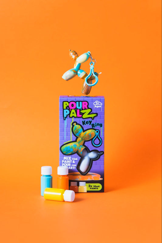 Pour Palz Mini Keyring Balloon Dog DIY Art Kit box with 3 paint bottles and a completed marbled teal and orange balloon dog keyring floating above on orange background